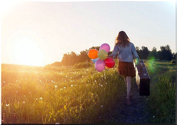 woman on a path with balloons and a suitcase